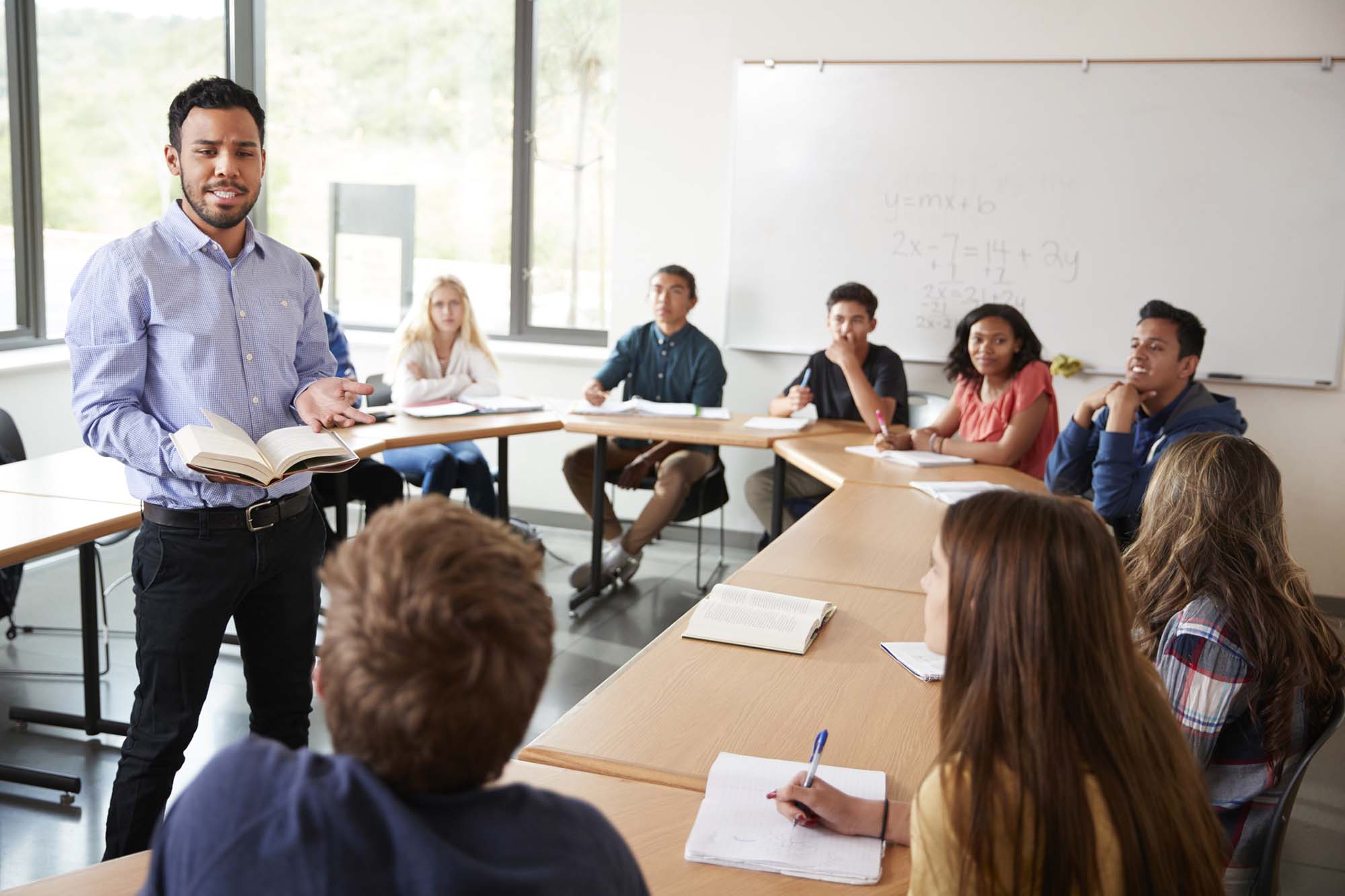 male high school tutor with pupils sitting around a desk